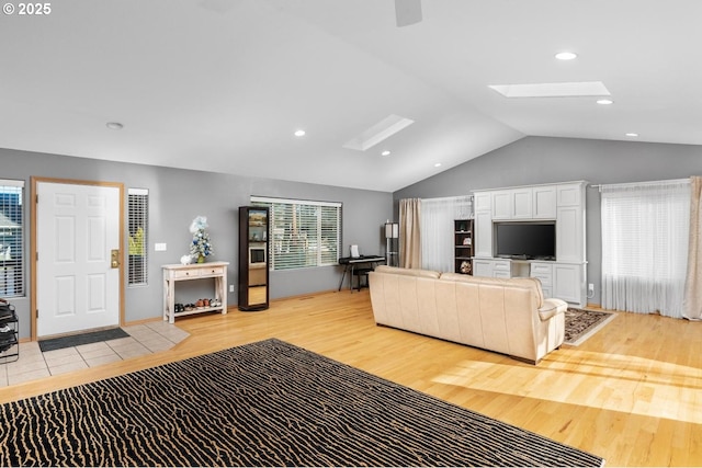 living room with lofted ceiling with skylight and light hardwood / wood-style flooring