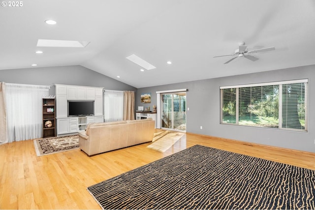 living room with ceiling fan, light wood-type flooring, and lofted ceiling with skylight