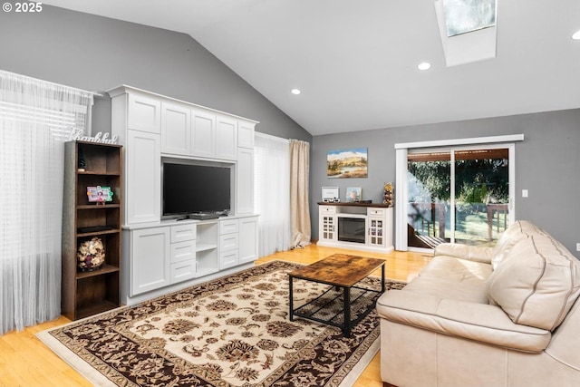 living room with lofted ceiling with skylight and light hardwood / wood-style flooring