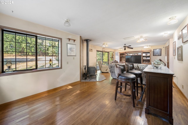 interior space featuring a kitchen bar, dark hardwood / wood-style flooring, dark brown cabinetry, ceiling fan, and a wood stove