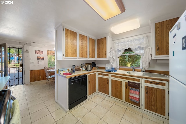 kitchen featuring stove, black dishwasher, light tile patterned floors, and wooden walls