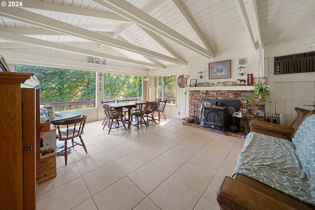 interior space featuring an AC wall unit, a wood stove, tile patterned flooring, and lofted ceiling with beams