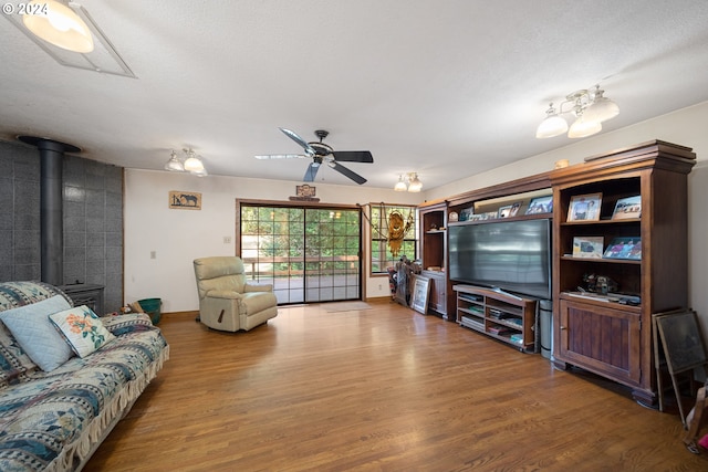 living room with hardwood / wood-style flooring, ceiling fan, and a wood stove