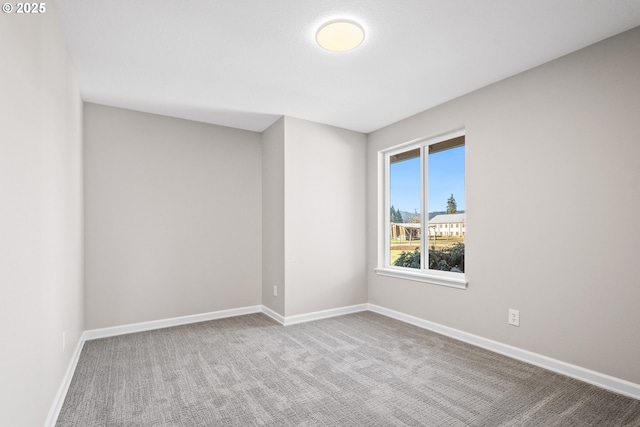 carpeted empty room featuring baseboards