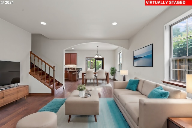 living room with dark wood-type flooring, a healthy amount of sunlight, and a notable chandelier