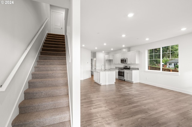 stairs featuring hardwood / wood-style floors and sink