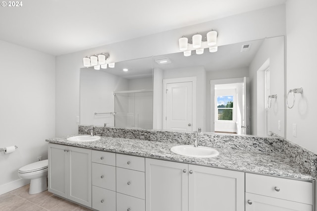 bathroom featuring tile patterned floors, vanity, toilet, and a shower with shower door