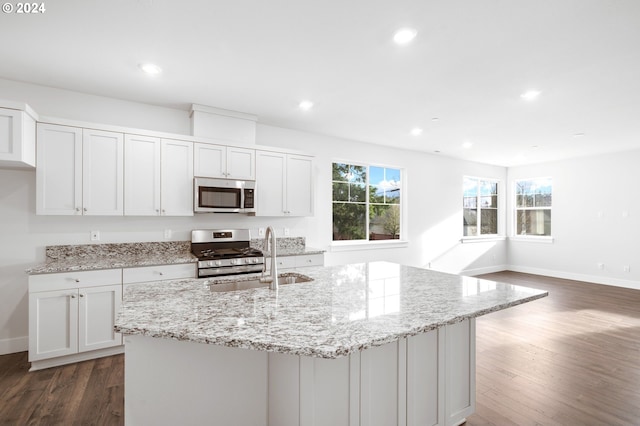 kitchen featuring light stone countertops, stainless steel appliances, sink, a center island with sink, and white cabinets