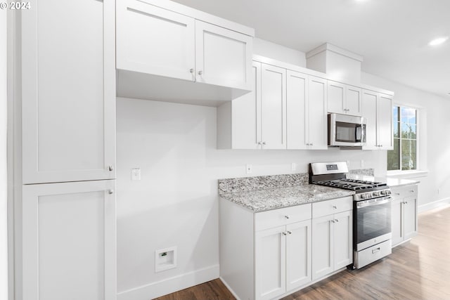 kitchen featuring dark hardwood / wood-style flooring, light stone countertops, white cabinetry, and stainless steel appliances