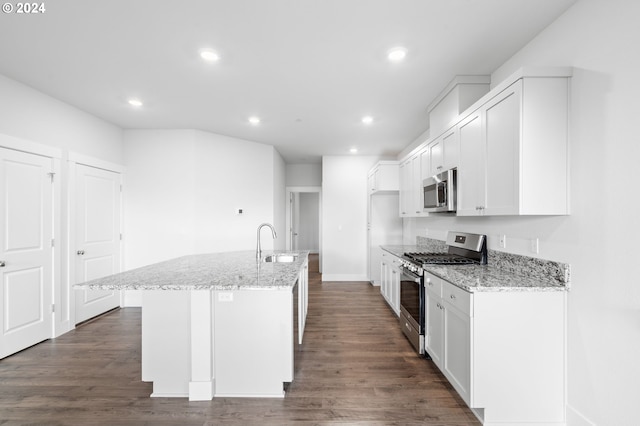 kitchen with light stone countertops, appliances with stainless steel finishes, a center island with sink, and sink