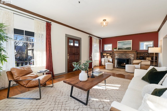 living room with a brick fireplace, ornamental molding, and light hardwood / wood-style floors