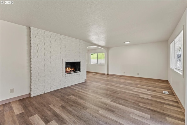 18765 SW Kinnaman Rd, Beaverton, OR 97078 - unfurnished living room with a brick fireplace, wood finished floors, a textured ceiling, and baseboards
