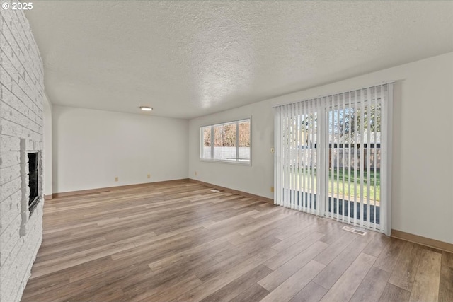 18765 SW Kinnaman Rd, Beaverton, OR 97078 - unfurnished living room featuring wood finished floors, a textured ceiling, a fireplace, and baseboards