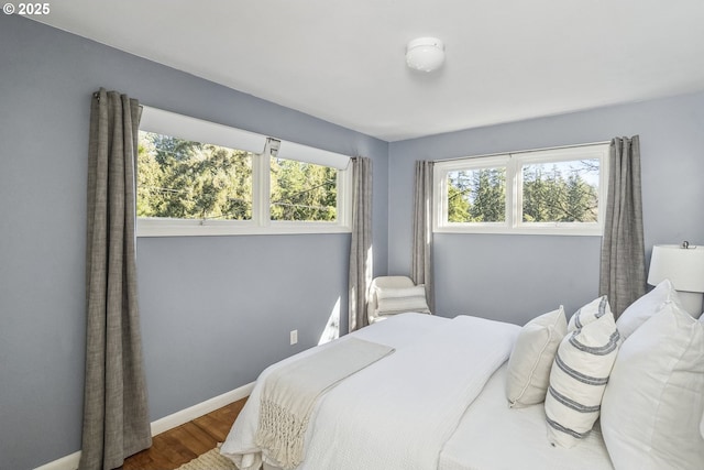 bedroom featuring multiple windows, baseboards, and wood finished floors