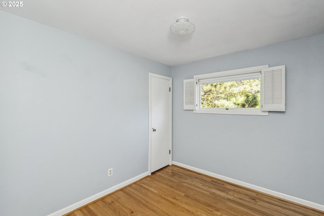 spare room featuring wood finished floors, visible vents, and baseboards