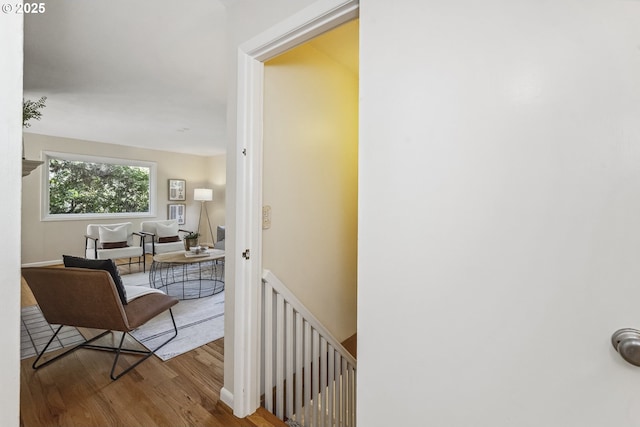 hall with wood finished floors and an upstairs landing