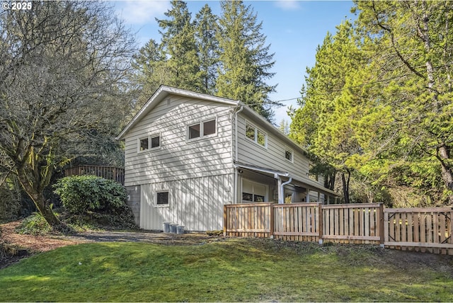 exterior space with a lawn, cooling unit, and fence