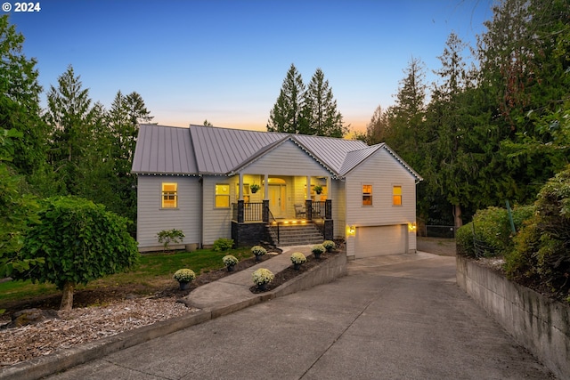 view of front of home featuring a garage, driveway, metal roof, and covered porch