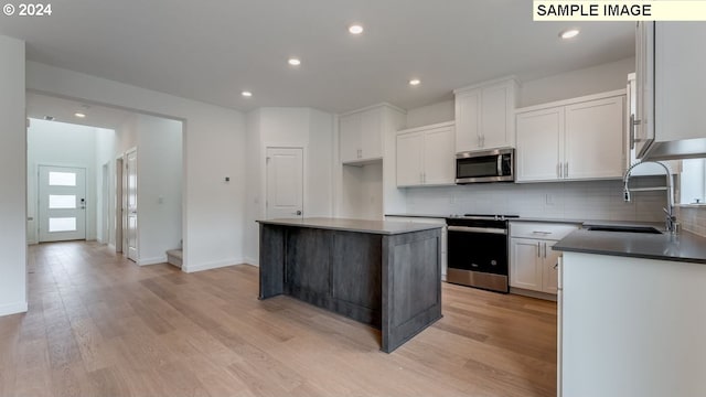 kitchen featuring light wood-type flooring, backsplash, stainless steel appliances, and a sink