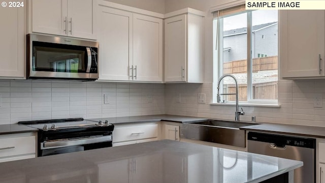 kitchen featuring stainless steel appliances, a sink, a wealth of natural light, and white cabinets