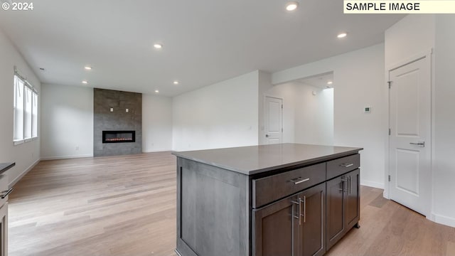 kitchen with a fireplace, a kitchen island, light wood-style flooring, and recessed lighting