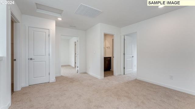 unfurnished bedroom featuring attic access, carpet floors, baseboards, and ensuite bathroom