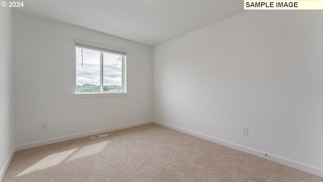 carpeted empty room featuring baseboards and visible vents