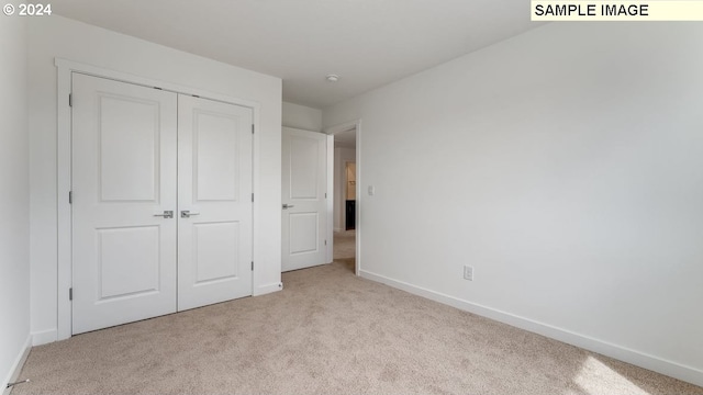 unfurnished bedroom featuring a closet, light carpet, and baseboards