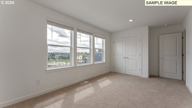 unfurnished bedroom featuring recessed lighting, a closet, visible vents, light carpet, and baseboards