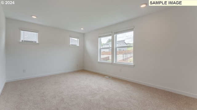 spare room featuring light carpet, recessed lighting, visible vents, and baseboards