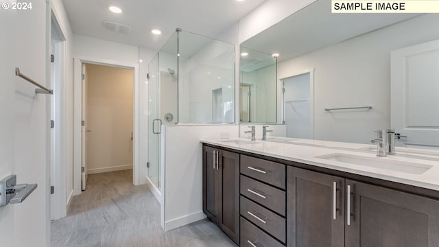 bathroom with double vanity, a spacious closet, a sink, and a shower stall