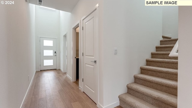 interior space with light wood-type flooring, baseboards, and stairs