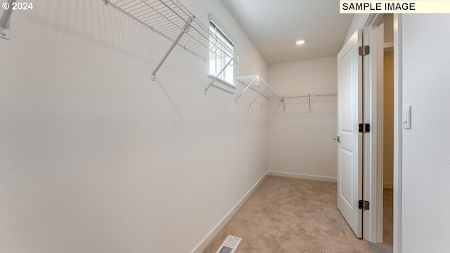 walk in closet with light colored carpet and visible vents