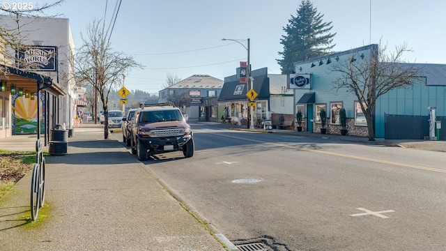 view of road featuring street lights, curbs, traffic signs, and sidewalks