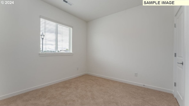 unfurnished room featuring light carpet, visible vents, and baseboards