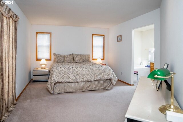 bedroom with ensuite bathroom and light carpet