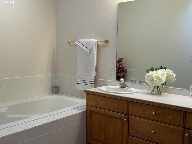 bathroom with tiled tub and vanity