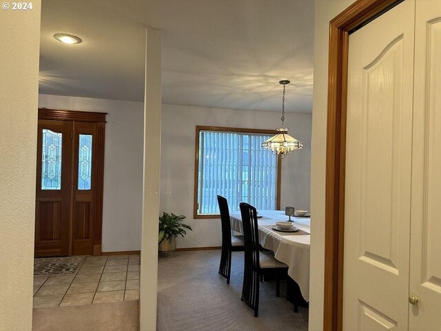 carpeted foyer entrance featuring a notable chandelier