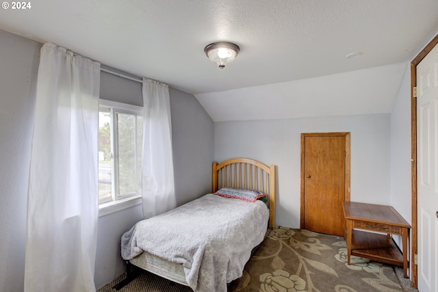 bedroom featuring vaulted ceiling and a textured ceiling