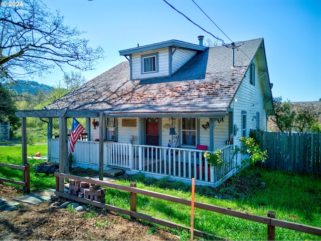 view of front facade featuring a high end roof, covered porch, and fence