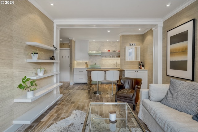 living room with wood-type flooring, crown molding, and sink