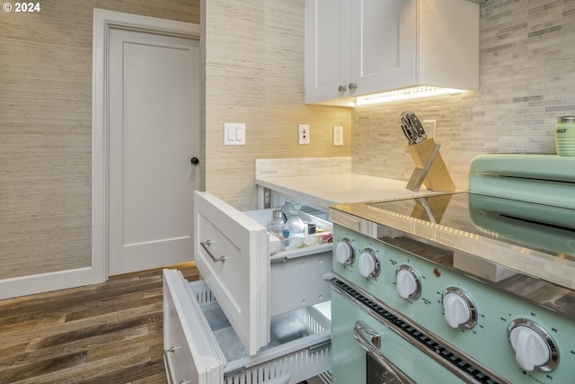 room details featuring range, tasteful backsplash, white cabinetry, and dark wood-type flooring