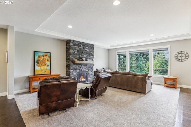 living room with a tray ceiling, a fireplace, and light wood-type flooring