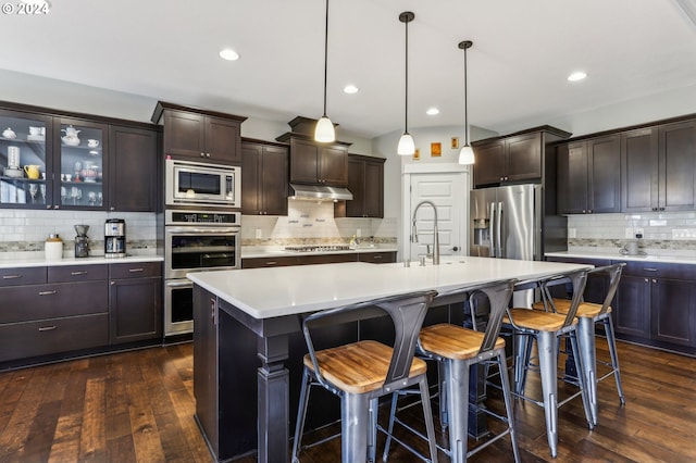 kitchen featuring a kitchen island with sink, sink, hanging light fixtures, dark hardwood / wood-style floors, and stainless steel appliances