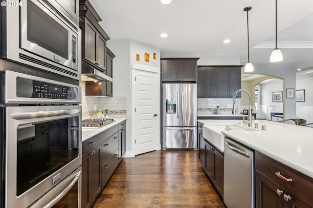 kitchen with dark hardwood / wood-style flooring, dark brown cabinetry, stainless steel appliances, sink, and decorative light fixtures