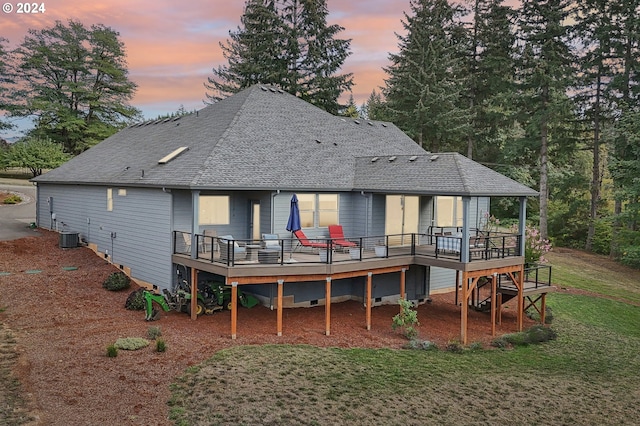 back house at dusk featuring a yard, central AC unit, and a deck