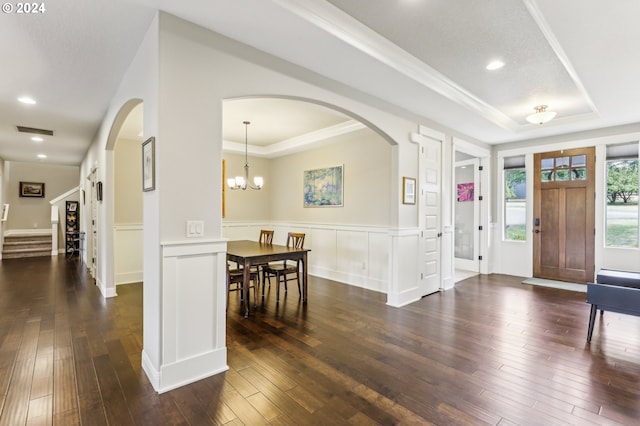 foyer entrance featuring dark hardwood / wood-style floors, a raised ceiling, and crown molding