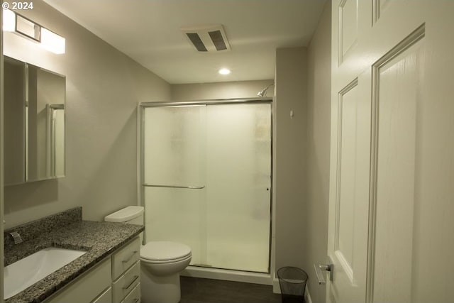 bathroom with hardwood / wood-style flooring, vanity, toilet, and a shower with shower door