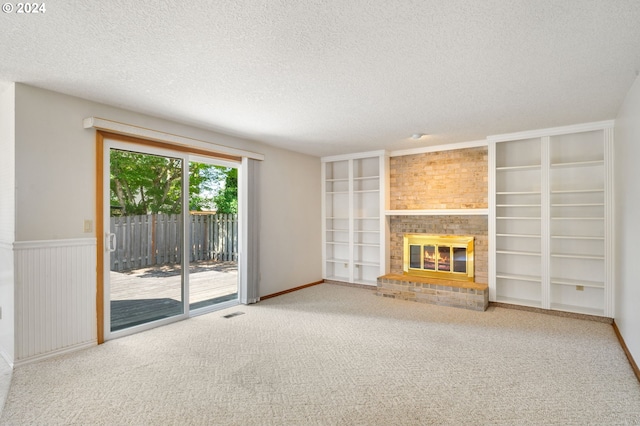 unfurnished living room featuring brick wall, light carpet, a textured ceiling, and a brick fireplace