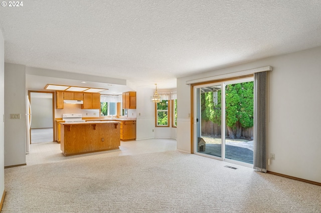 unfurnished living room featuring a notable chandelier, light colored carpet, and a textured ceiling